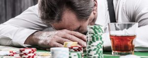 Sad man with his head down at a poker table.