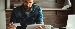 Man looking at tablet with credit card in hand.