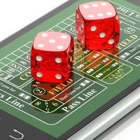 Dice sitting on top of a mobile phone displaying a craps board