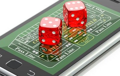 Dice sitting on top of a mobile phone displaying a craps board